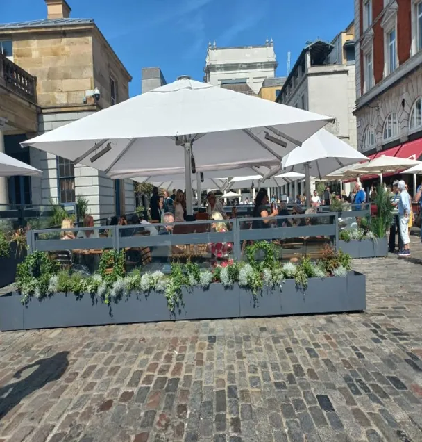 RÜZGAR KIRICI, Covent Garden — şemsiyeli teras ve saksılarla birleşen rüzgar kırıcı panelleri